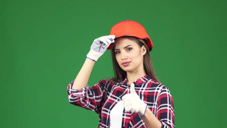 Attractive young female construction worker contractor smiling seductively wearing hardhat showing thumbs up on chromakey confidence feminism equality unity profession engineering.の写真素材