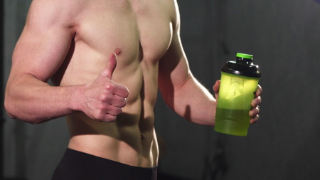 Cropped close up of a shirtless ripped man with sexy muscular body and perfect abs holding water...