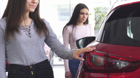 Cropped shot of a woman buying a new car at the dealership, choosing automobile with her best friend. Two female friends checking out new cars for sale. Retail, driving, transportation concept.の写真素材