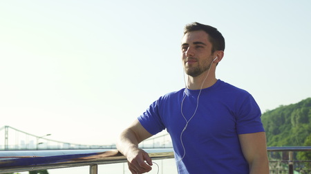 Low angle shot of a handsome bearded athletic man smiling, looking away, relaxing after morning...