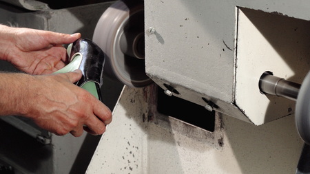 Sliding cropped shot of a professional shoemaker polishing shoe sole on a craft grinding machine....