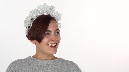 Happy young woman laughing joyfully, wearing snowflakes headband. Beautiful cheerful young woman celebrating Christmas or New Year wearing snowflake costume, isolatedの写真素材