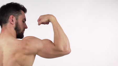 Rearview shot of a shirtless athletic bearded man flexing his biceps. Cropped shot of a ripped male athlete showing off his strong powerful arms, copy space. Gym, muscles conceptの写真素材