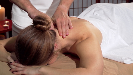 Professional masseur doing relaxing back massage for female client. Unrecognizable woman receiving neck and back massage at spa center. Therapy, treatment conceptの写真素材