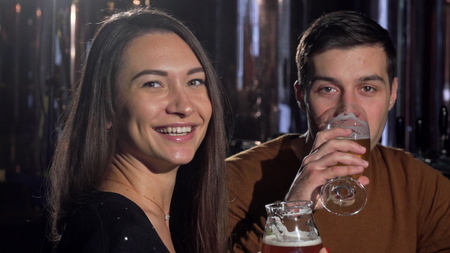 Beautiful woman smiling to the camera after clinking glasses with boyfriend. Happy couple...