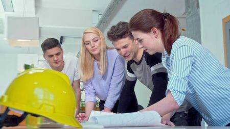 Group of young engineers discussing architectural blueprints. Professional architects working on a building construction plan at their office. Teamwork, engineering conceptの写真素材