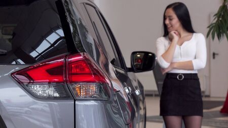 Selective focus on car lights, woman choosing new auto at the dealership. Beautiful woman examining automobile on sale at car salon. Female customer buying car. Drive, safety conceptの写真素材