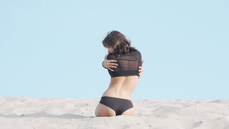 Slim dark haired female dancer performing outdoors in the desert. Young athletic woman dancing on sand outdoors on a hot sunny day. Femininity, sensuality conceptの写真素材