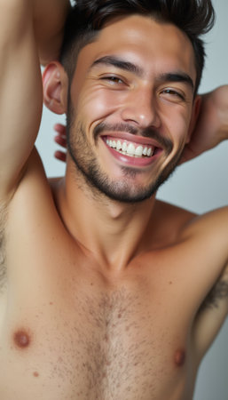 A cheerful young man with a well-groomed beard and tousled hair beams with a bright smile, showcasing his confidence and charm. His bare chest and relaxed pose exude a sense of warmth and approachability, inviting viewers to share in his joy.の素材