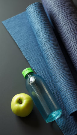 A vibrant green apple rests beside a clear water bottle on elegantly rolled blue fabric, creating a fresh and inviting scene. The contrasting textures and colors evoke a sense of health and vitality, perfect for promoting wellness and lifestyle themes.の素材