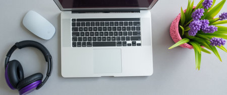A sleek laptop sits on a minimalist desk, accompanied by stylish headphones and a cheerful pot of purple flowers. This inviting workspace exudes creativity and productivity, perfect for inspiring focus and innovation.の素材