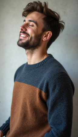A cheerful young man with a stylish beard smiles brightly, wearing a cozy sweater that blends earthy tones. His joyful expression and relaxed demeanor create an inviting atmosphere, perfect for capturing the essence of happiness and comfortの素材