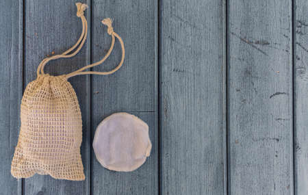Ecology and conscious consumption concept. Organic natural cotton pads and eco bag on blue wooden...