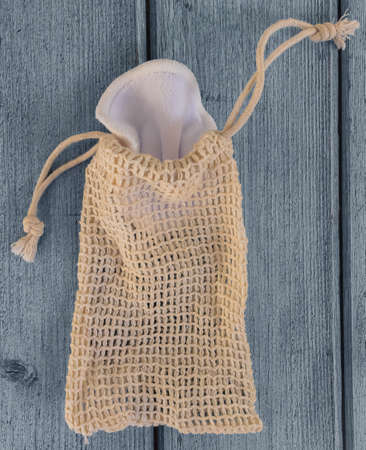Organic cotton reusable pads for make-up removal in knitted eco bag on blue wooden background. sustainable lifestyle concept. Top view, close-up. Zero waste, eco-friendly.の写真素材