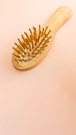hair care concept. Eco accessory for hair care. Wooden hair brush on pink background. Healthy and beauty hair. hair loss protection. scalp massage. Verticalの写真素材