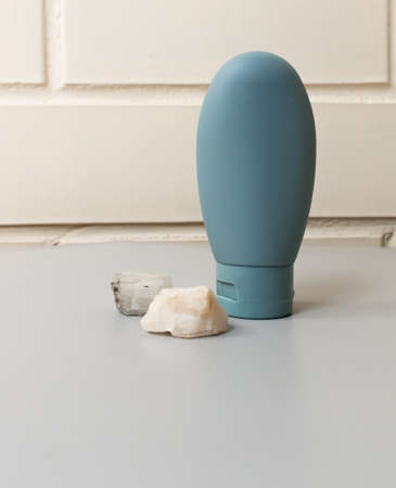 Travel reusable cosmetic bottle and natural stone. Zero waste beauty product. Concept of vacation...