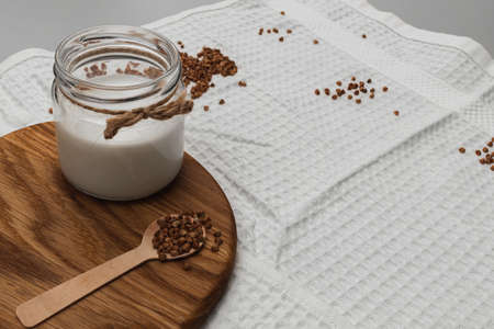 Vegan milk concept. Jar with alternative dairy product and buckwheat on wooden board. healthy...