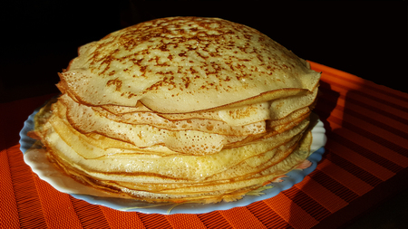 photo with a plate of freshly baked Russian pancakes on a black and red backgroundの写真素材