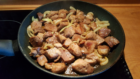 pan with large pieces of pork, fried with onionsの写真素材