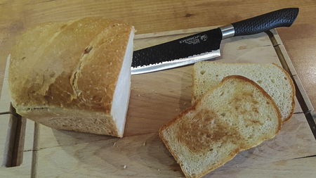 slice of bread on an old wooden board with a black knifeの写真素材
