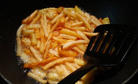 creative photo of french fries fried in a black panの写真素材