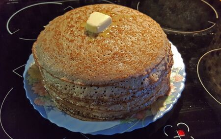 photo a lot of buckwheat pancakes on a stove with a slice of melting butterの写真素材