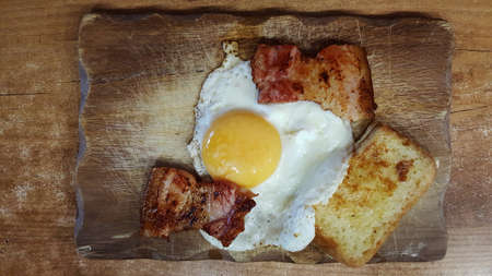 photo top view of fried eggs with pieces of fried bacon and croutonsの写真素材