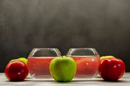 photo apples green and red tomatoes with two glasses on mixed backgroundの写真素材