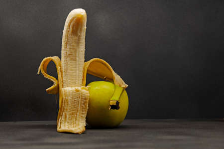 photo of a half-peeled banana hugging a green appleの写真素材