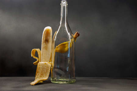 photo of a semi-peeled banana hugs a bottle horizontal frameの写真素材
