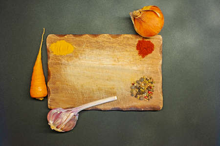 photo of pepper, turmeric, garlic, onion, paprika on a wooden board on a dark backgroundの写真素材