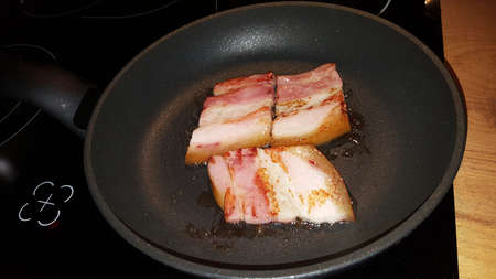 photo of fried eggs from one egg on a black frying pan close-upの写真素材
