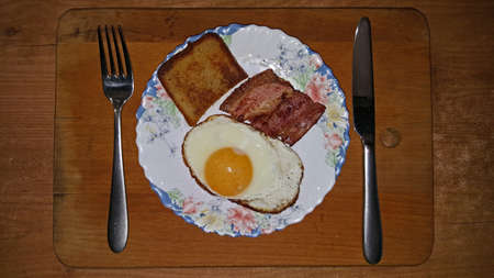photo of fried eggs from one egg on a black frying pan close-upの写真素材