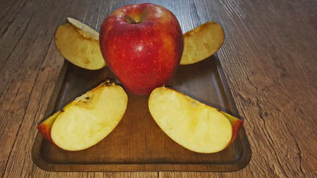 a whole apple and apple slices on a wooden square plate in perspectiveの写真素材