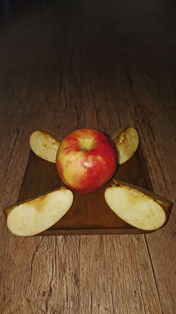 a whole apple and apple slices on a wooden square plate in perspectiveの写真素材
