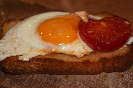art photo of fried eggs with tomato slices fried in butter on toast close-upの写真素材