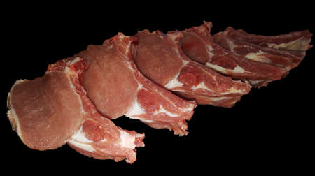 photo of isolated pork tenderloin on a rib cut into pieces on a board on a black backgroundの写真素材