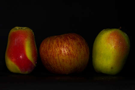 three red and green apple in drops of water on a black backgroundの写真素材