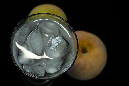 glass with ice and frozen apples close-up on black backgroundの写真素材