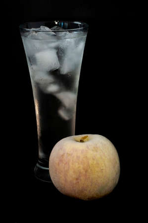 glass with ice and a frozen apple close-up on a black backgroundの写真素材
