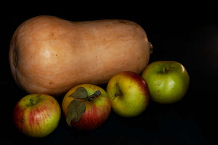 horizontal photo of pumpkin and ripe autumn apples close-up on black backgroundの写真素材