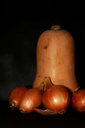 vertical photo of a pear-shaped pumpkin and onion close-up on a black backgroundの写真素材