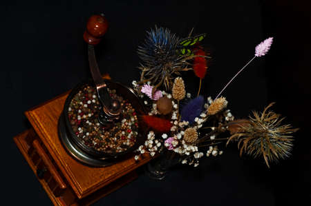 horizontal photo of a pepper mill and a bouquet of dried flowers close-up on a black backgroundの写真素材