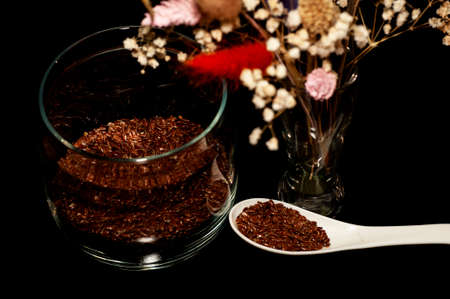 vertical art photo of flax seeds in a jar and spoon with a bouquet of dried flowers on a black backgroundの写真素材