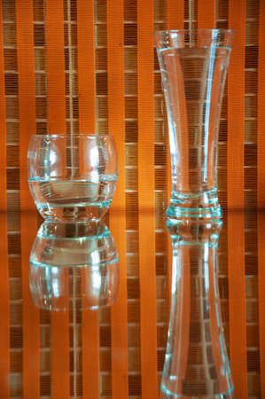 glasses with water and reflections on an orange checkered backgroundの写真素材