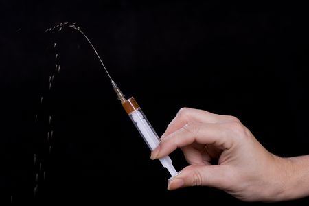 Syringe with a drug dose in a hand of the addictの写真素材