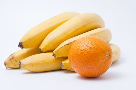 Cluster of ripe tasty bananas and  orange on a light background の写真素材