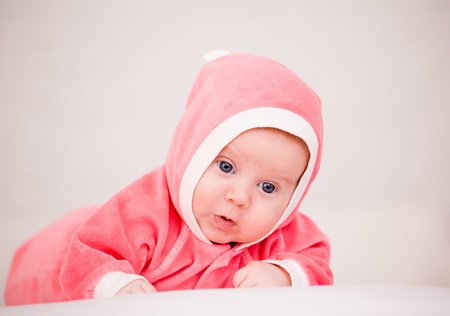baby in is bright-pink overalls lies on a stomachの写真素材