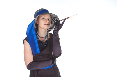 The young beautiful woman in a dress for cocktails  and a hat,  holds a mouthpiece in a hand.  A...