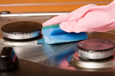 hand of the person in a rubber glove cleans a kitchen gas cookerの写真素材